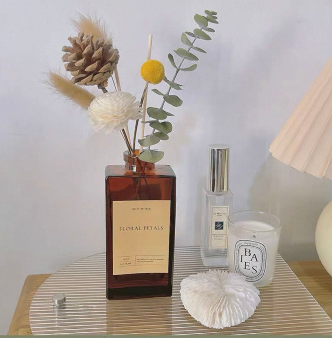 Decorative items including a bottle labeled 'Floral Petals', a small candle, and a vase with flowers on a table.