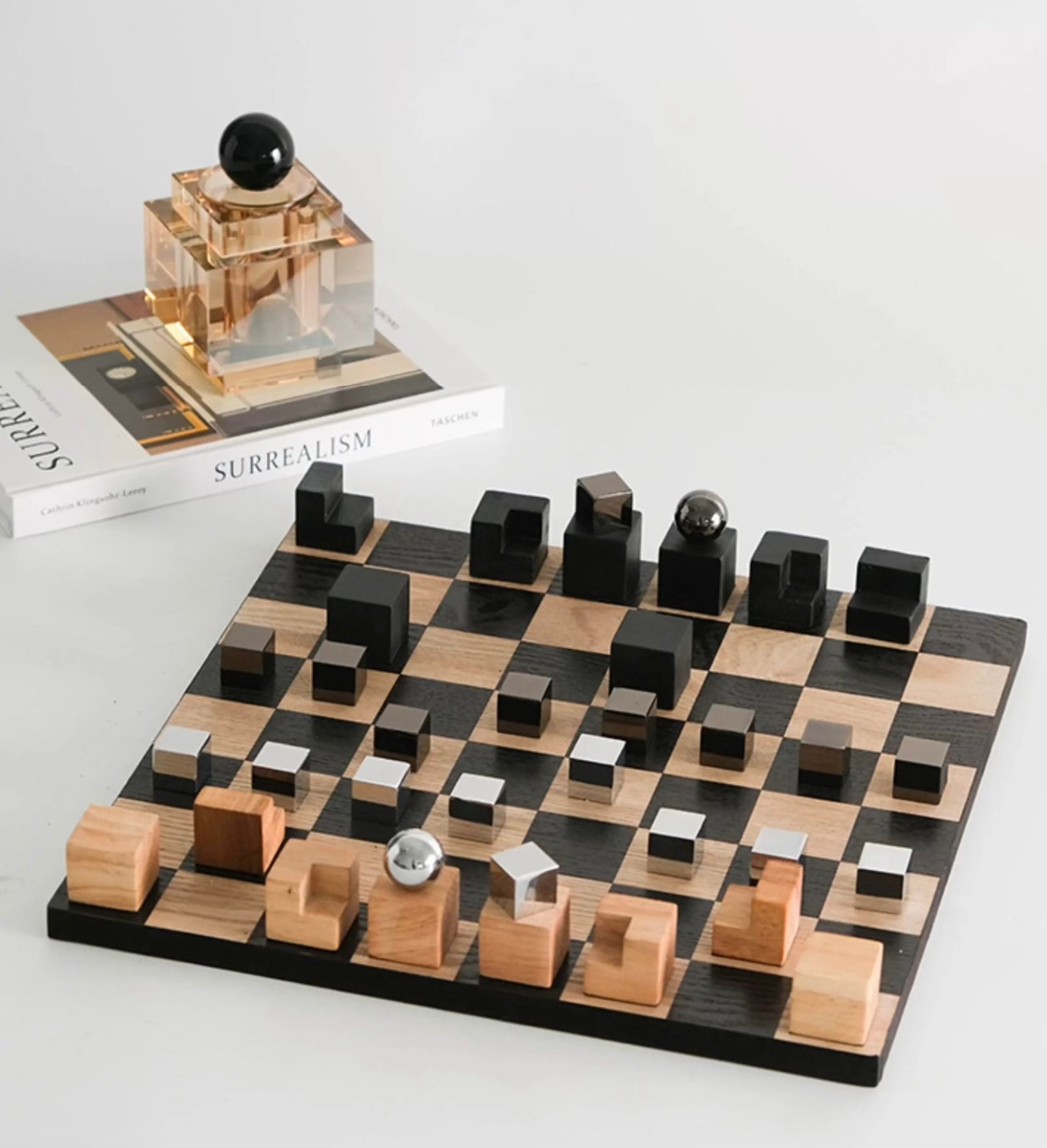 Wooden chessboard with black and brown pieces on a white surface