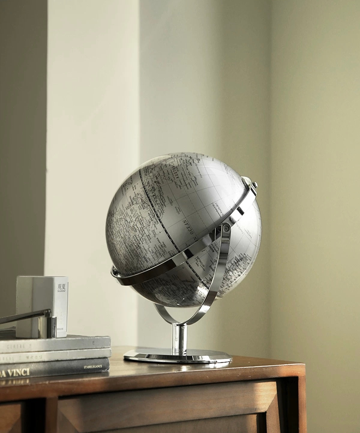 Silver globe on a wooden table with a neutral background