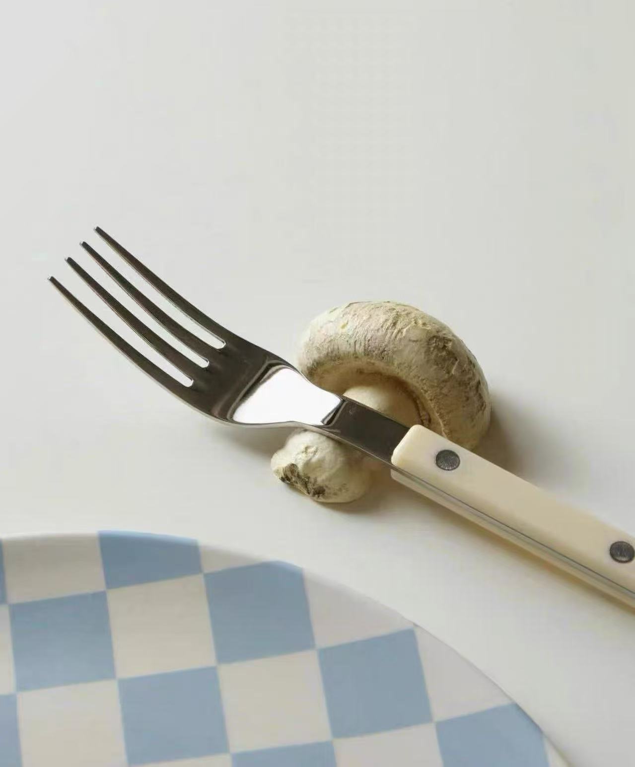 Fork and knife with a mushroom on a white surface