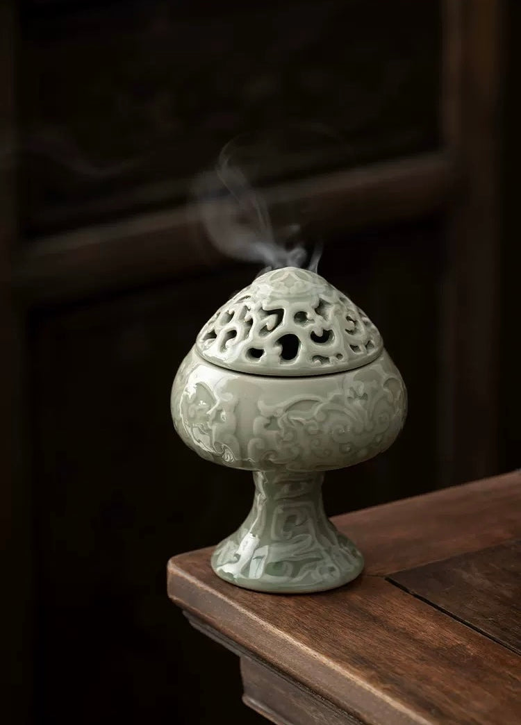 Decorative ceramic incense burner with smoke on a wooden surface