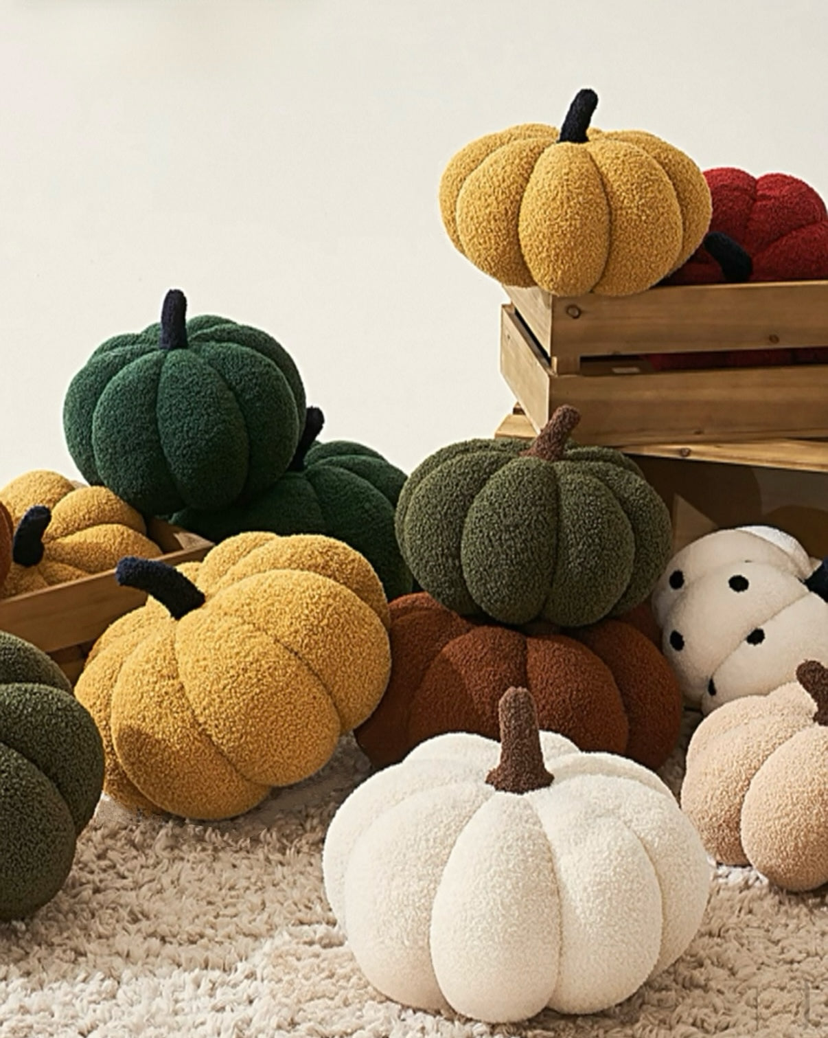 Collection of colorful pumpkin-shaped cushions on a textured surface with a wooden crate in the background.