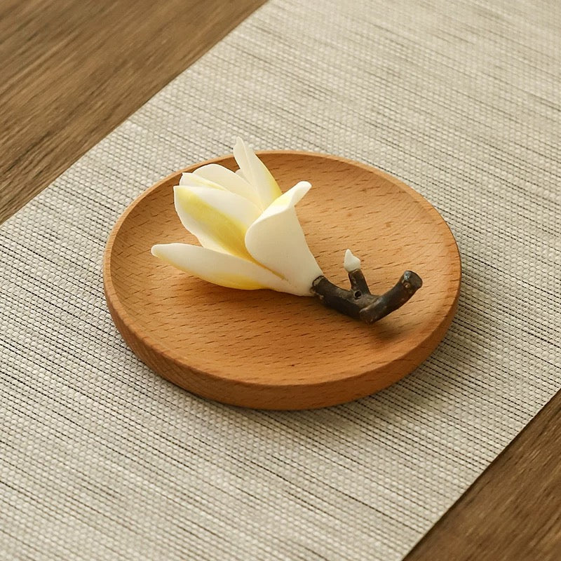 Wooden coaster with a white flower and branch on a textured surface