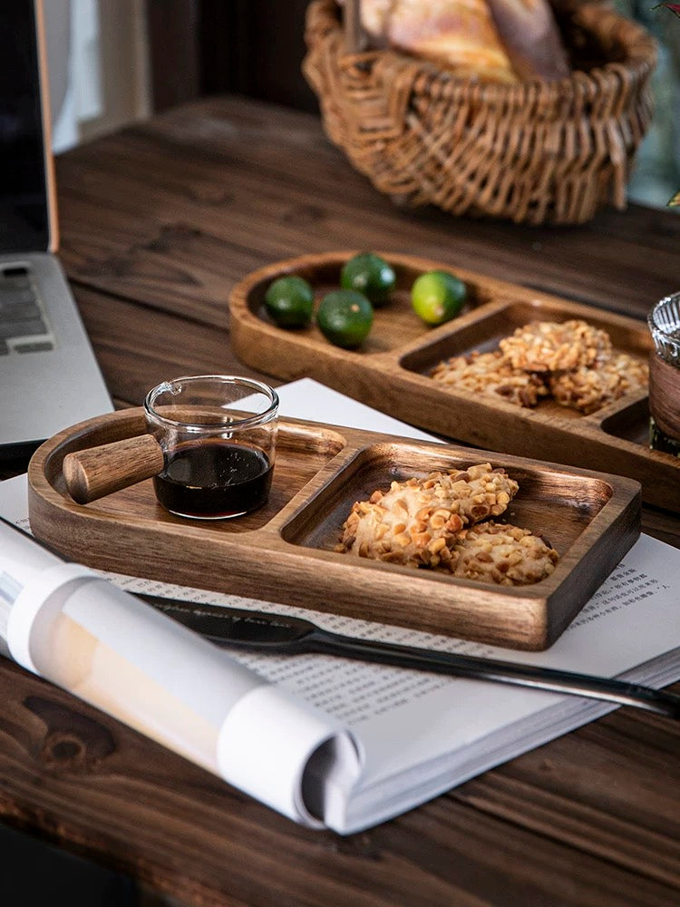 Wooden tray with cookies, a glass of dark liquid, and limes on a wooden table.