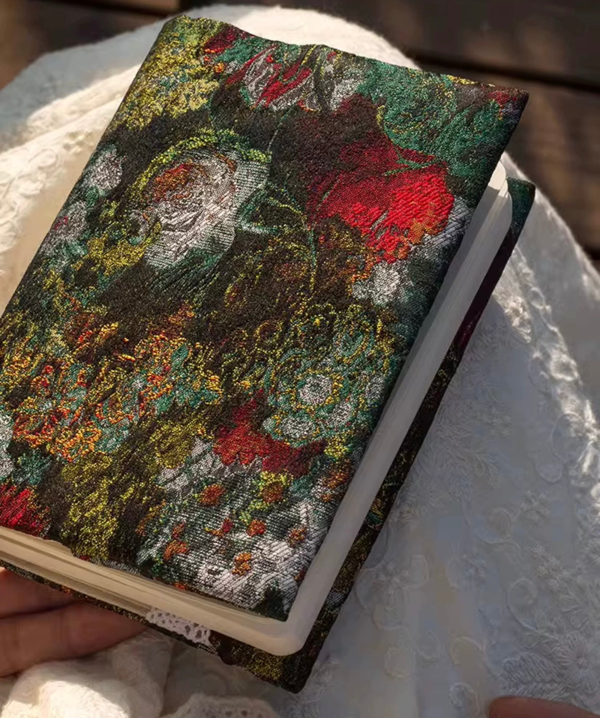 Notebook with a textured floral cover held on a textured surface