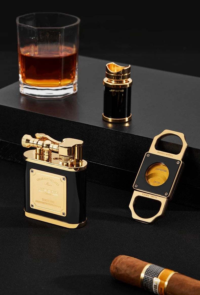 Set of black and gold smoking accessories including a lighter, bottle opener, and glass on a dark surface.
