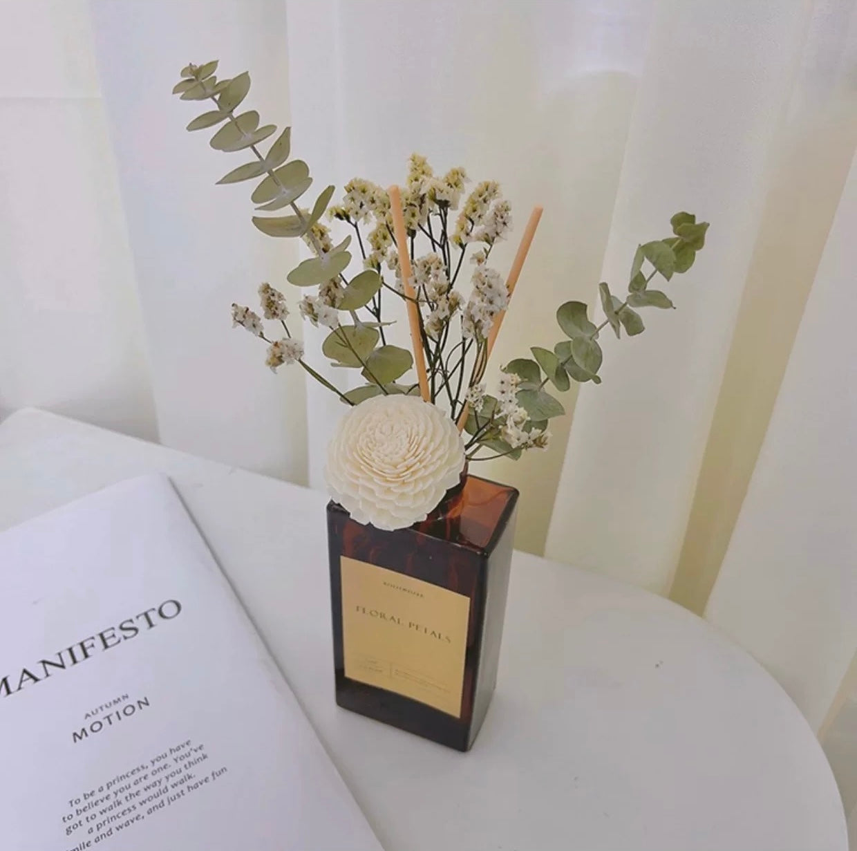 Decorative vase with flowers on a surface next to an open book