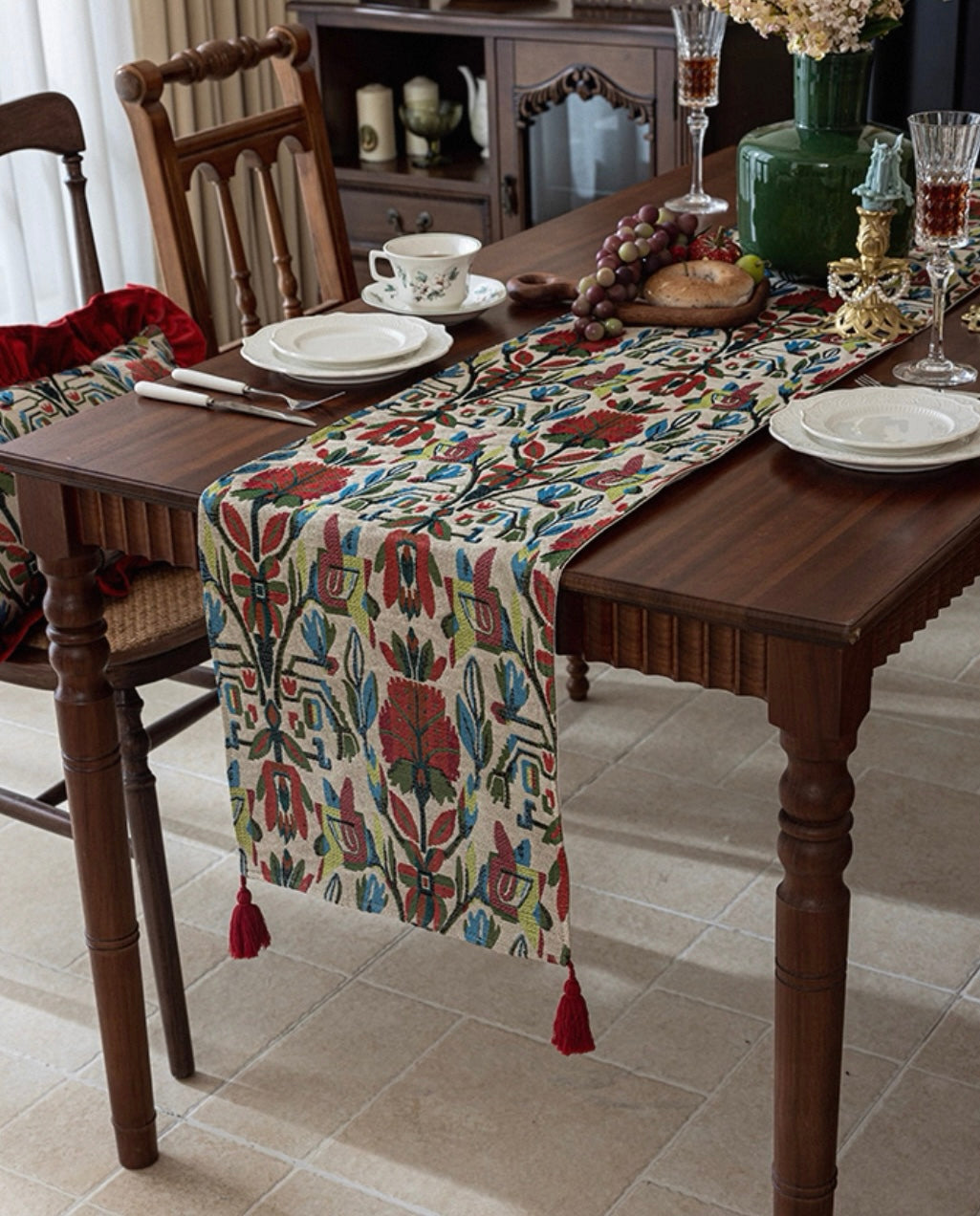 Dining table set with a patterned table runner, plates, and glasses on a wooden table.