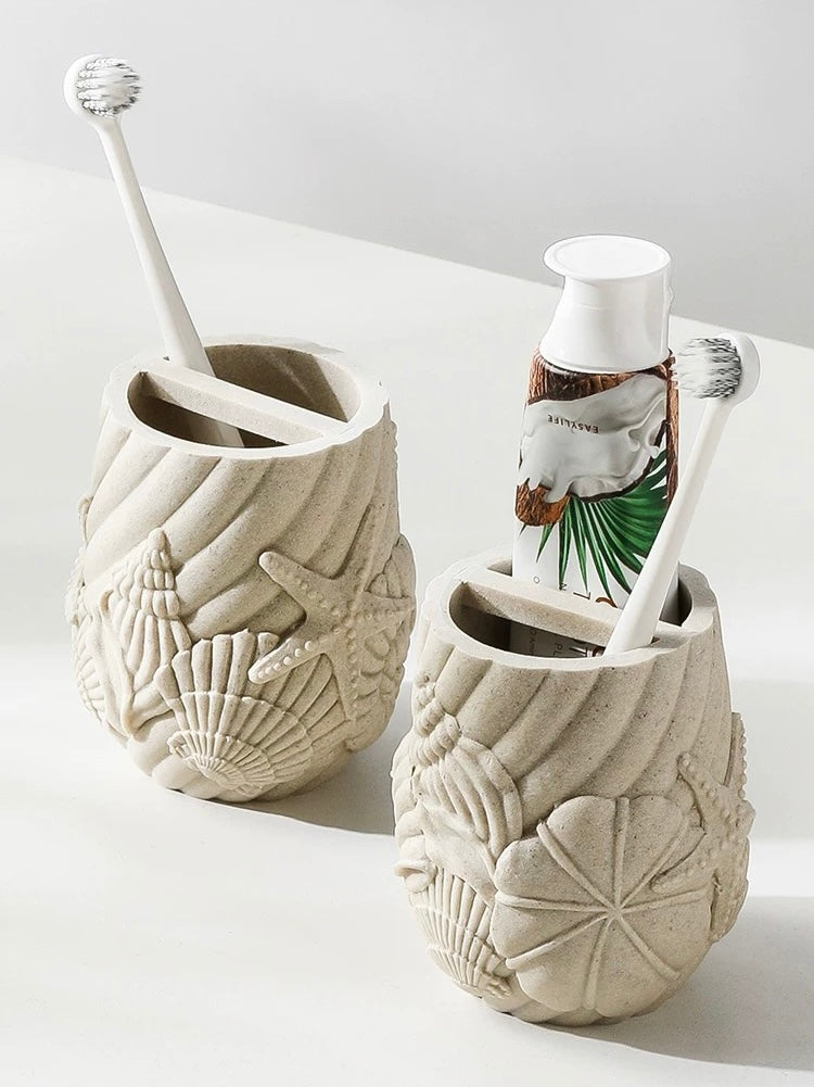 Two ceramic toothbrush holders with beach-themed designs on a white surface.