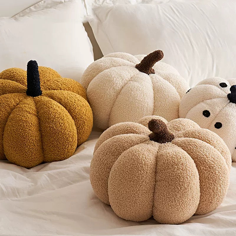 Three textured pumpkins in gold, beige, and white on a soft surface.