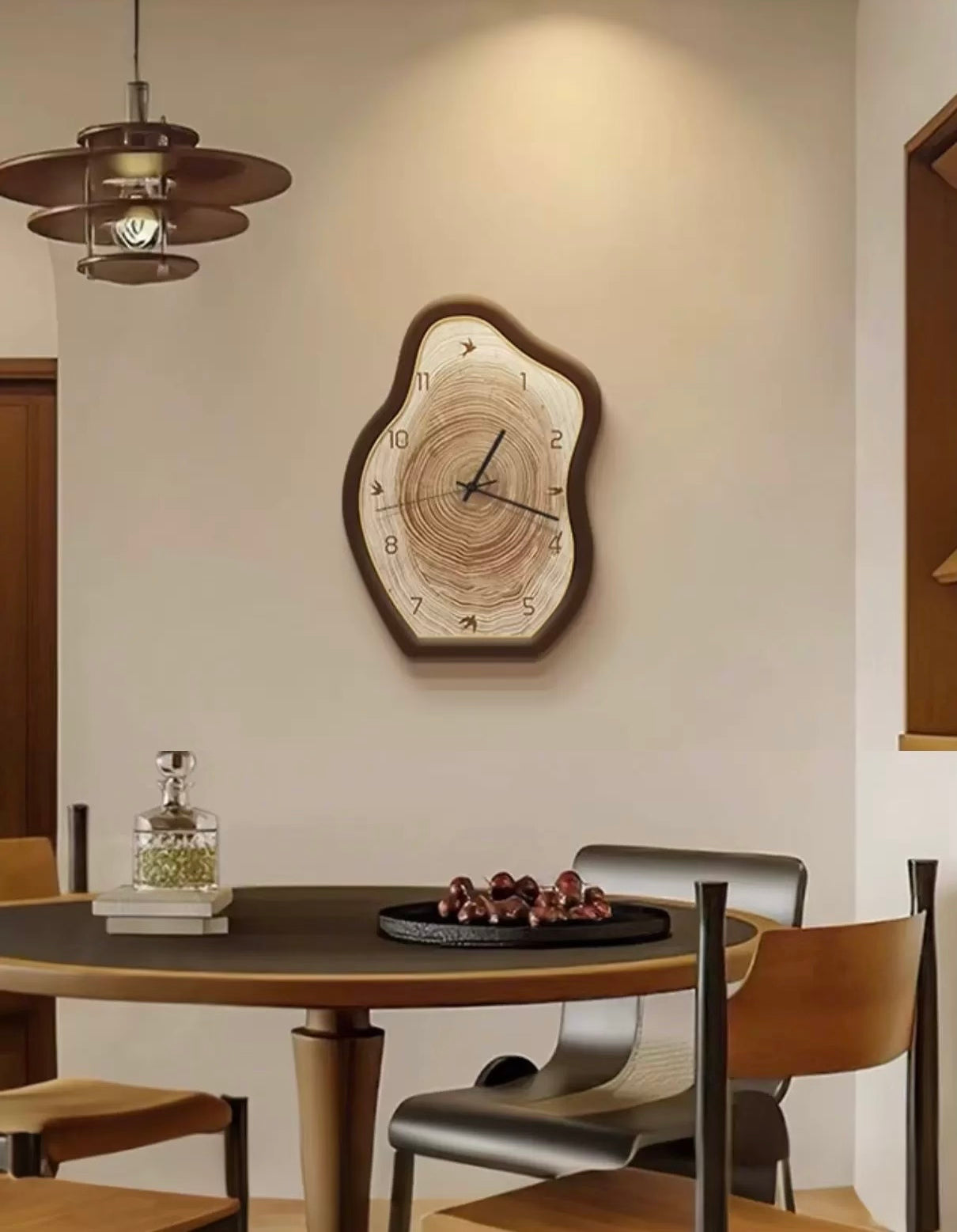 Wooden wall clock on a wall above a dining table with chairs.
