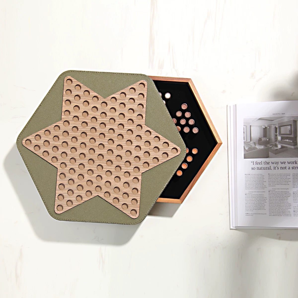 Hexagonal wooden puzzle with star design on a white surface next to a magazine.