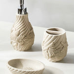 Set of ceramic bathroom accessories with shell designs on a light background