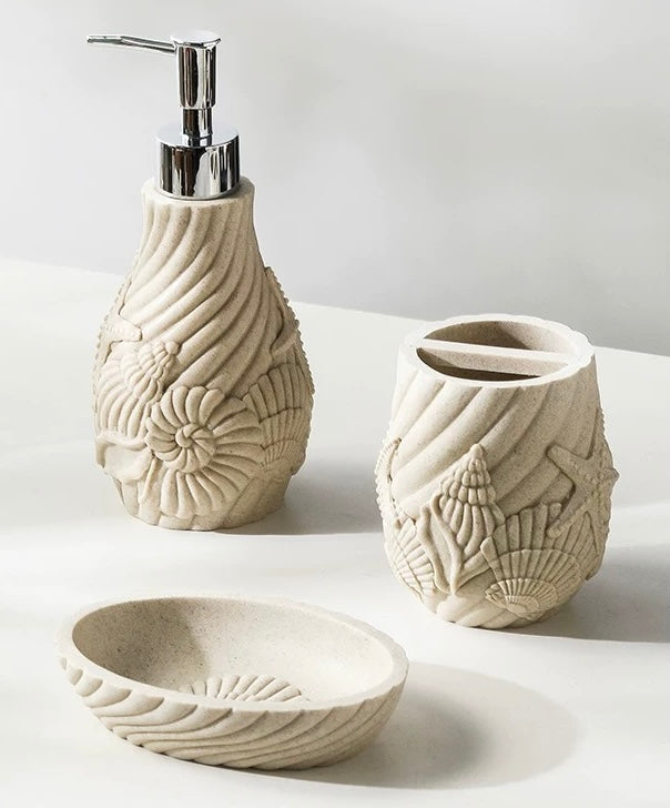 Set of ceramic bathroom accessories with shell designs on a light background
