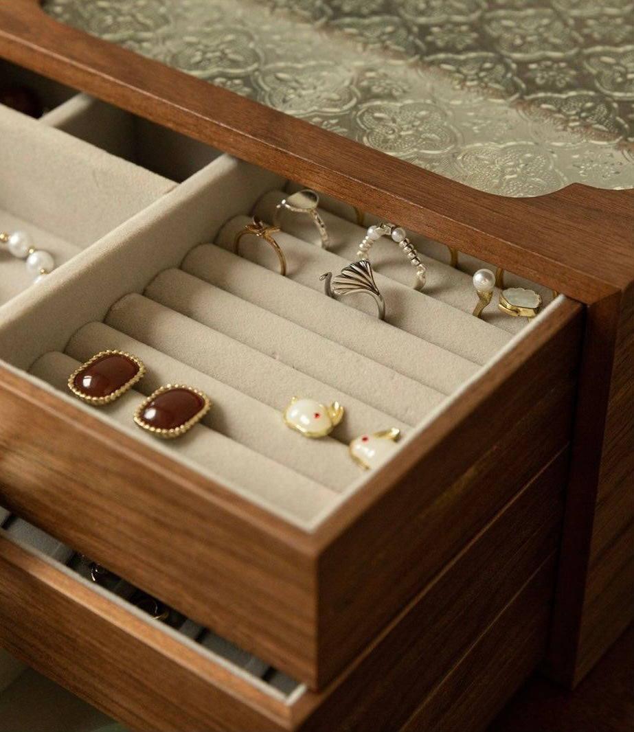 Wooden jewelry box with rings and earrings on a textured surface