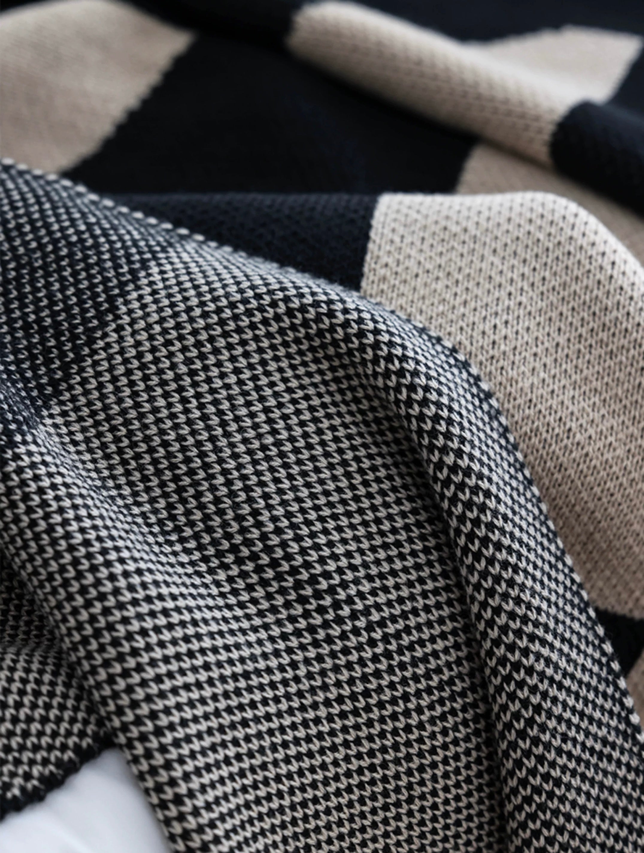 Close-up of a textured fabric with a checkered pattern in black, white, and beige.