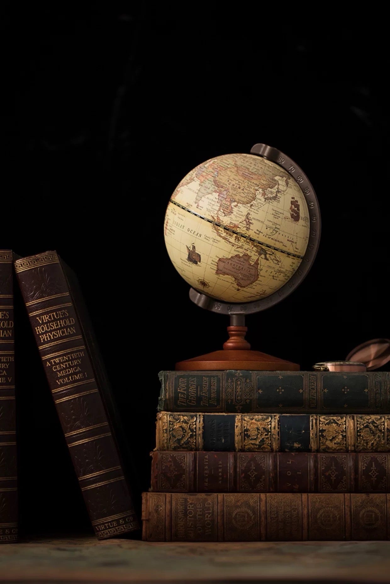 Vintage-style globe on a stack of old books with a dark background