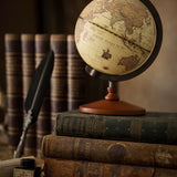 Vintage globe on a stack of old books with a feather quill and inkwell in the background.