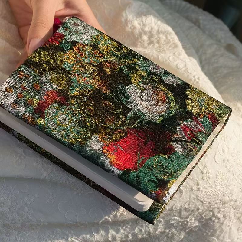 Floral patterned notebook held by a hand on a textured surface