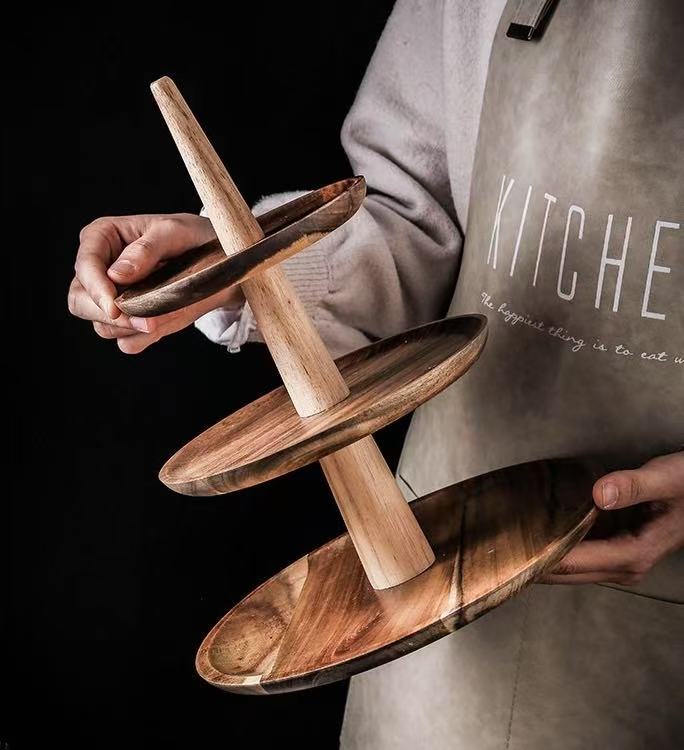 Person holding a wooden tiered stand with a dark background