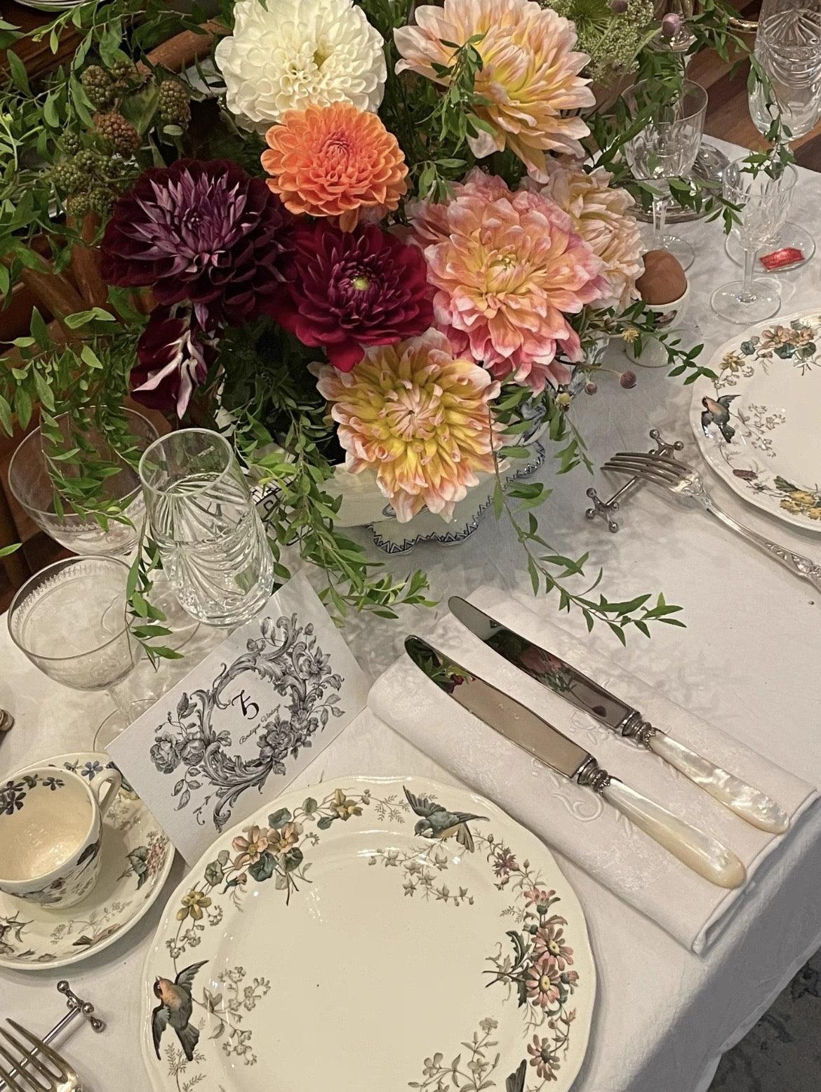 Elegant table setting with floral centerpiece, plates, and cutlery on a white tablecloth.