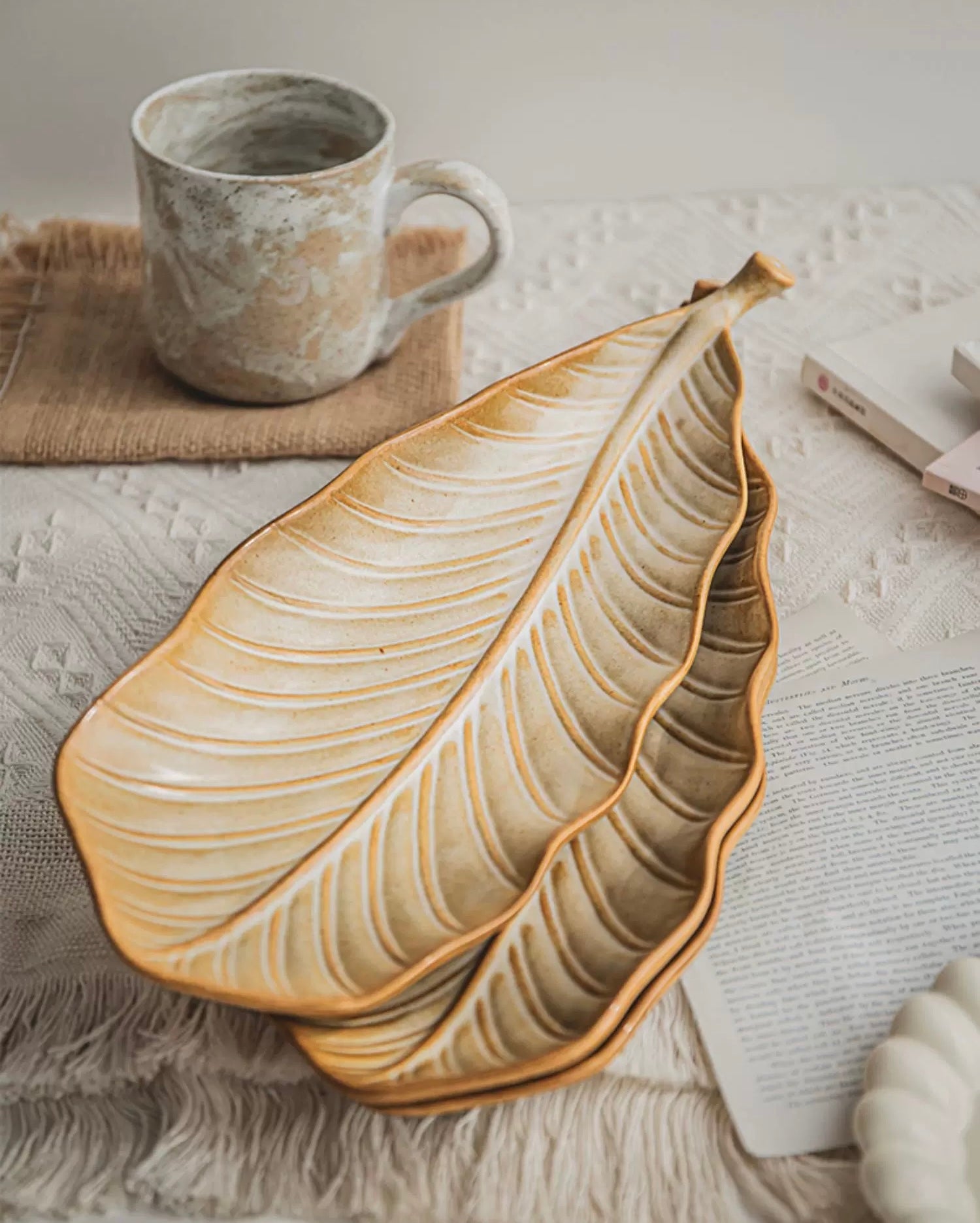 Ceramic leaf-shaped platter and mug on a textured surface
