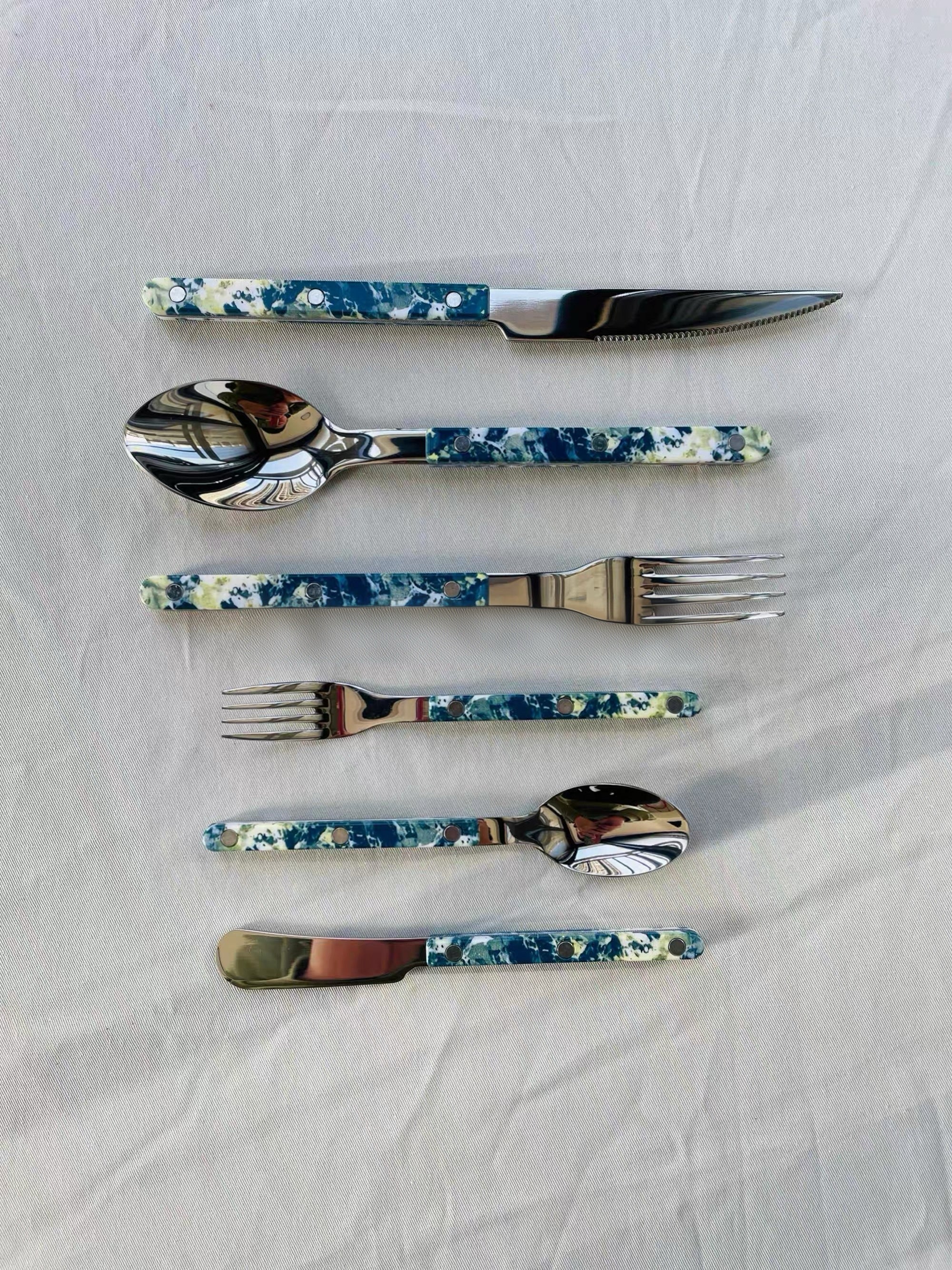 Set of floral-patterned cutlery on a white fabric background