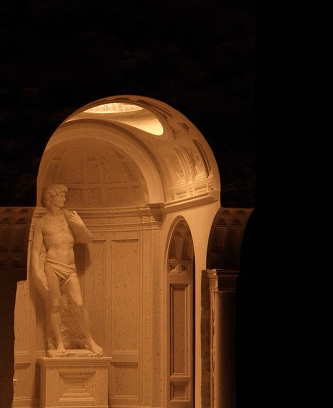 Statue of a man in a classical architectural setting with a dark background