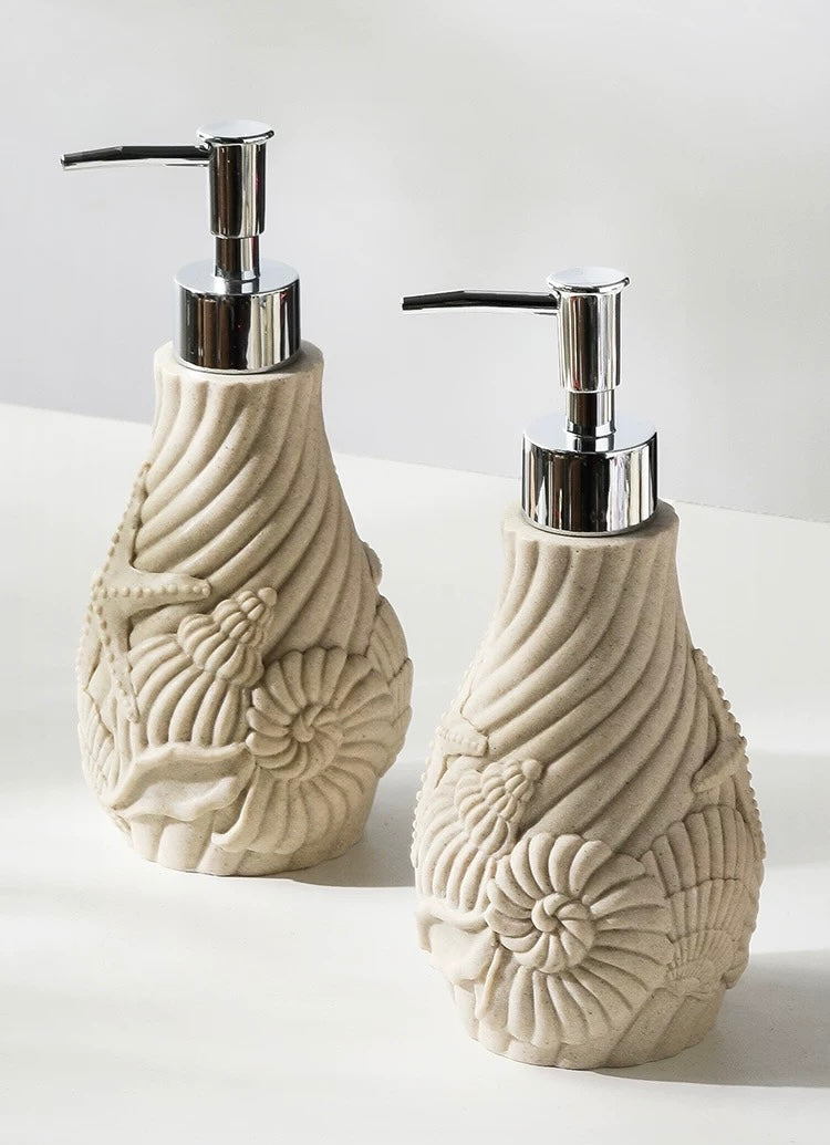Two decorative soap dispensers with shell designs on a white background