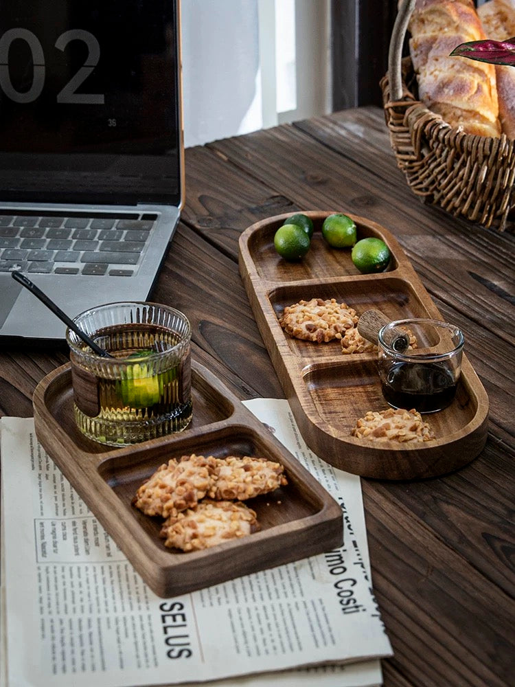 Wooden trays with snacks and drinks on a wooden table with a laptop and newspaper.