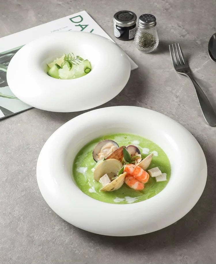 Two bowls of green soup with seafood on a gray surface.