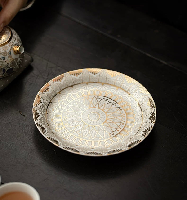 Decorative ceramic plate with gold patterns on a dark surface