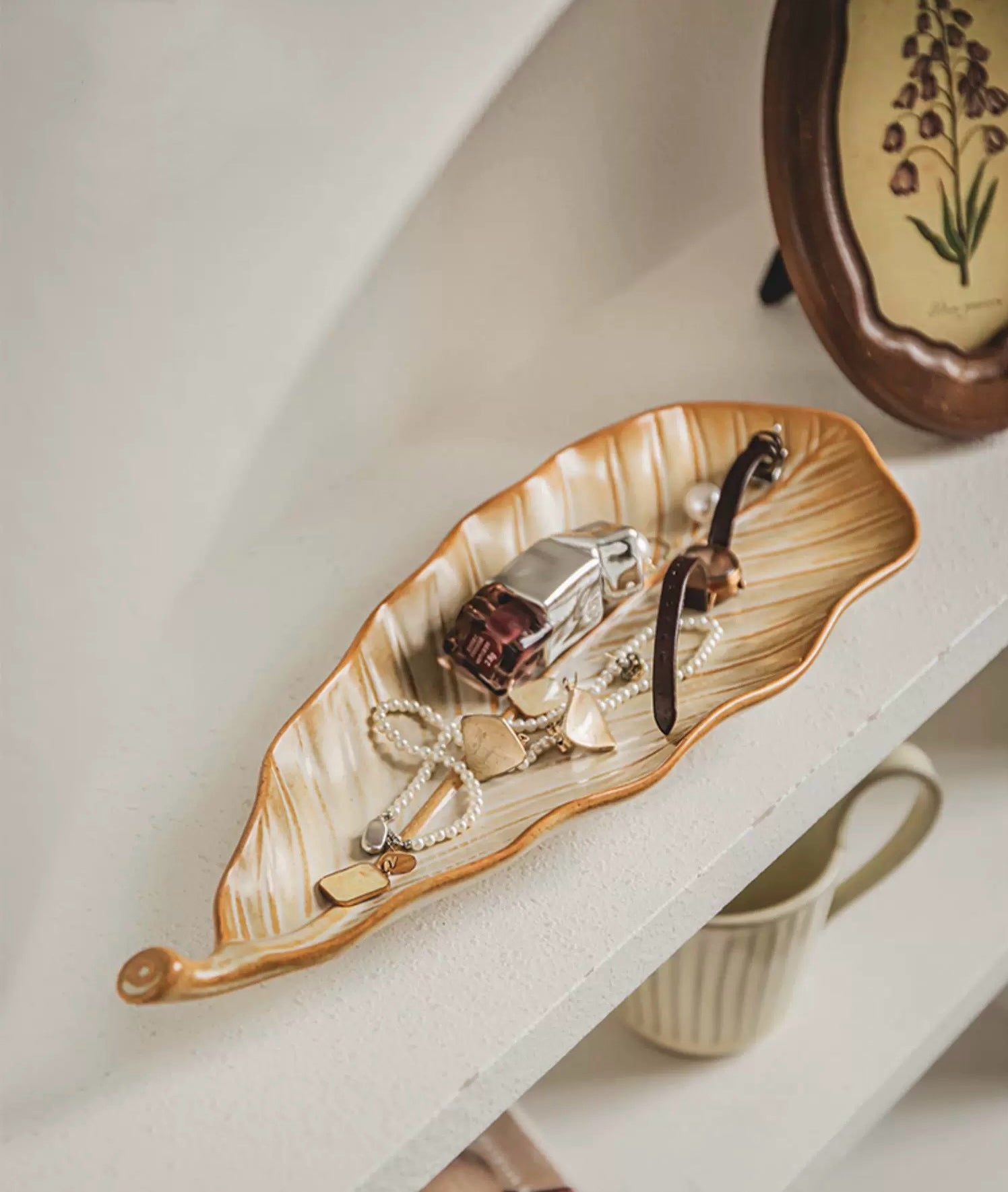 Decorative leaf-shaped tray with jewelry on a shelf