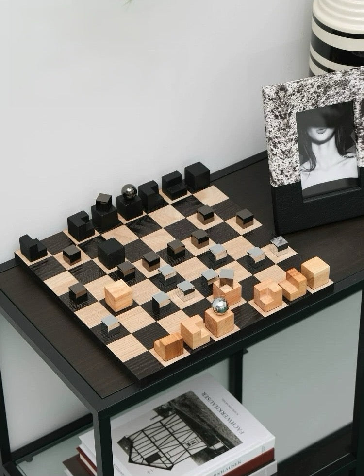 Wooden chessboard with black and light wood pieces on a table.