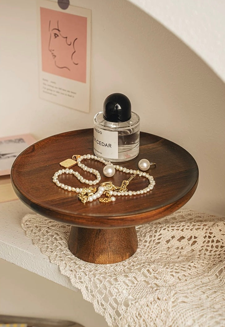 Wooden stand with jewelry and a bottle of perfume on a lace tablecloth.