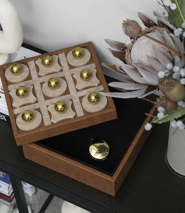 Wooden tic-tac-toe game set with gold pieces on a dark surface.