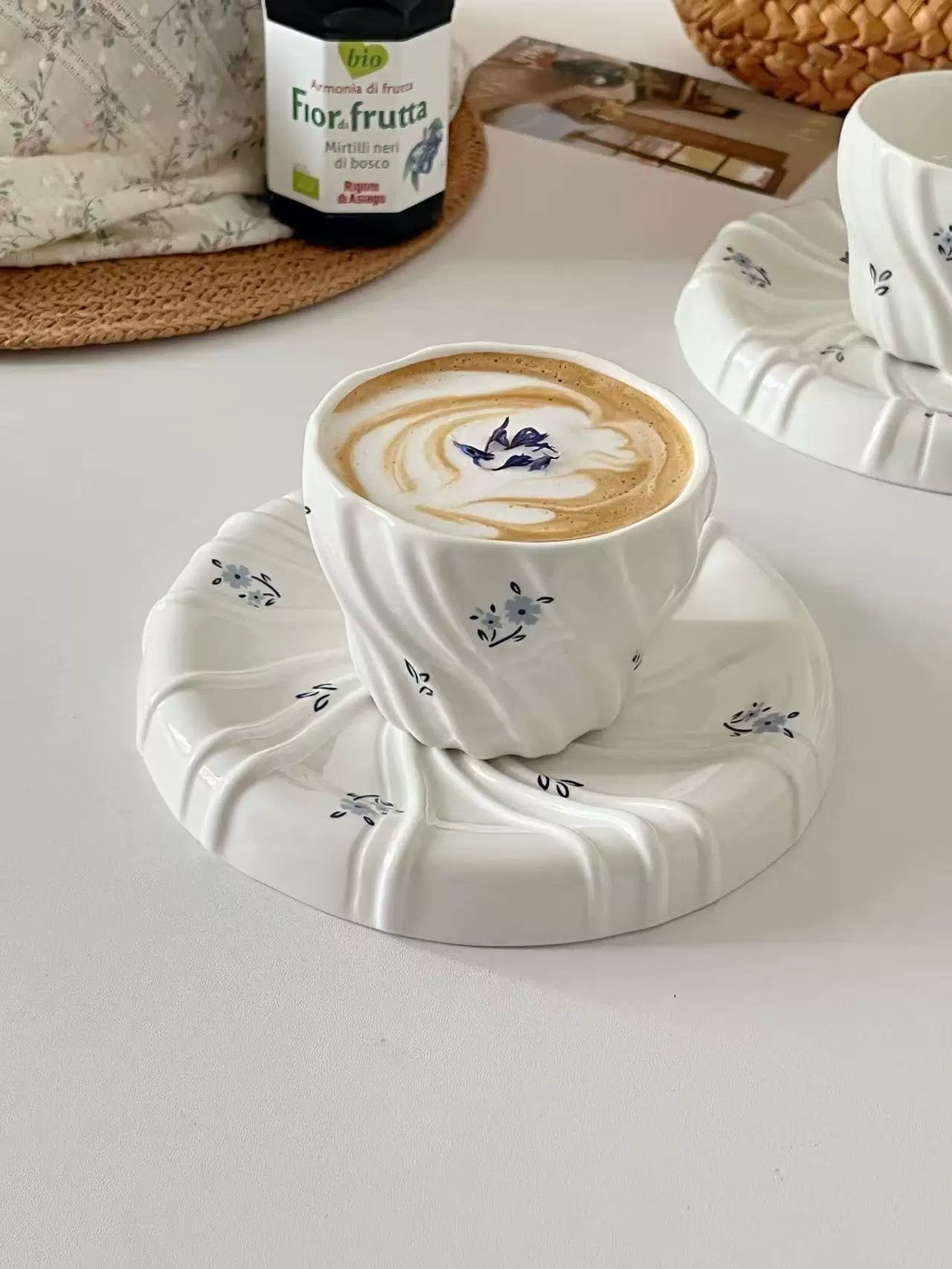 Cup of coffee with latte art on a decorative coaster on a light surface.