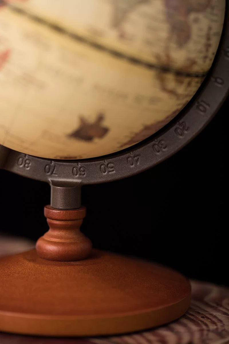 Close-up of a vintage-style globe with a wooden base on a dark background