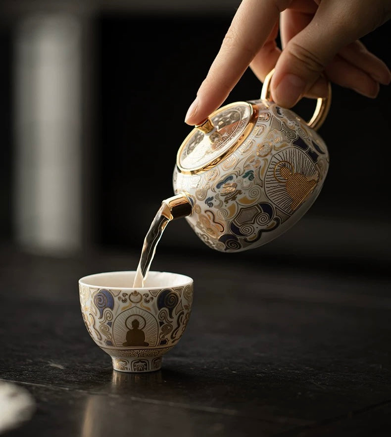 Tea being poured from an ornate teapot into a matching cup on a dark surface.