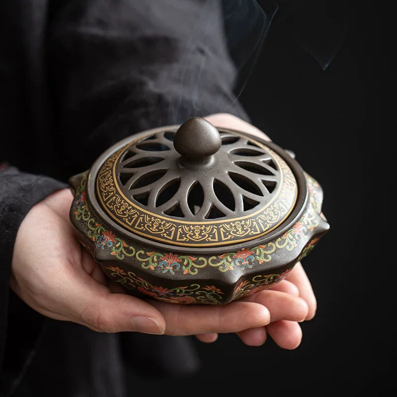Person holding a decorative incense burner with intricate designs.