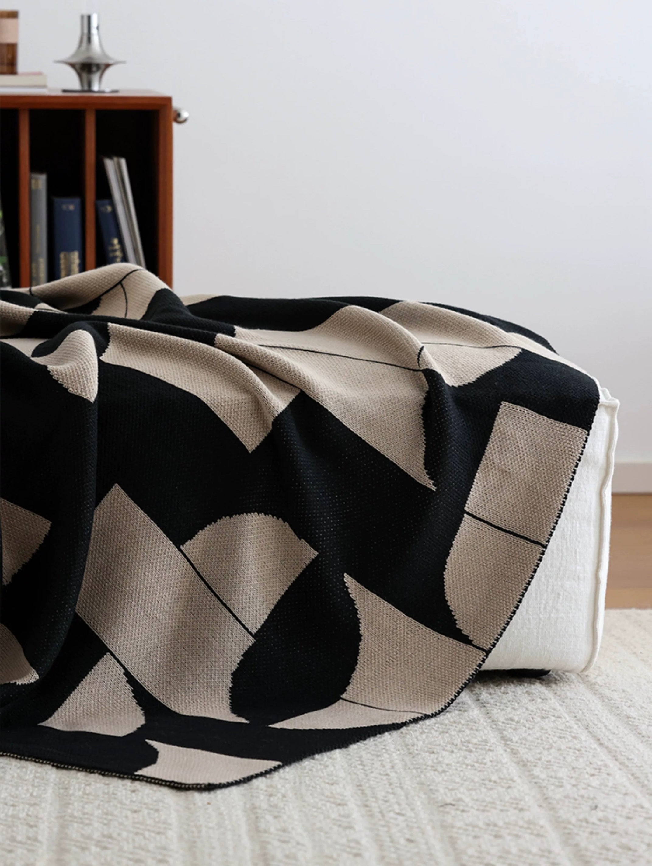 Black and beige patterned throw blanket on a sofa in a living room setting.