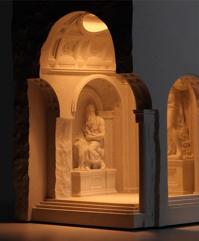 Stone sculpture of a seated figure in an archway with warm lighting
