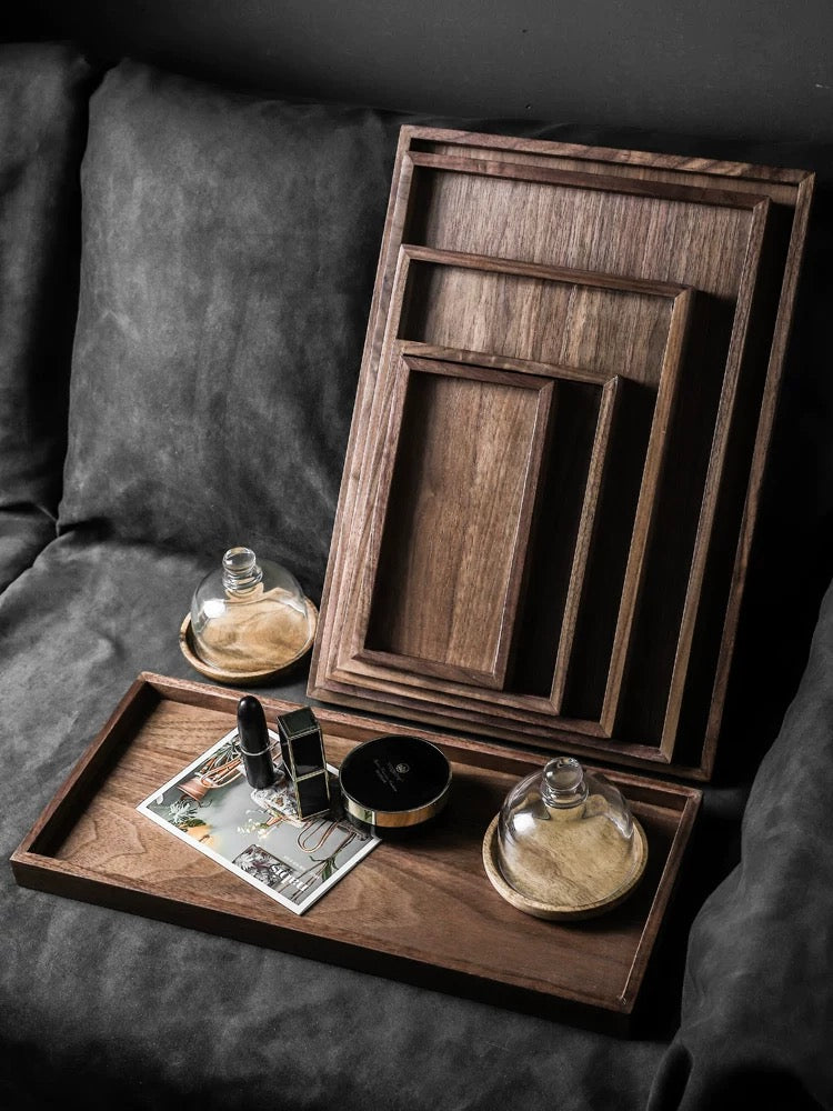 Set of wooden trays on a dark surface with decorative items.