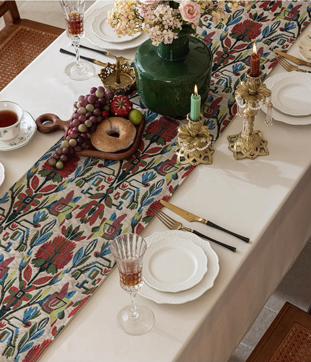 Elegant table setting with decorative tablecloth, plates, glasses, and candles.