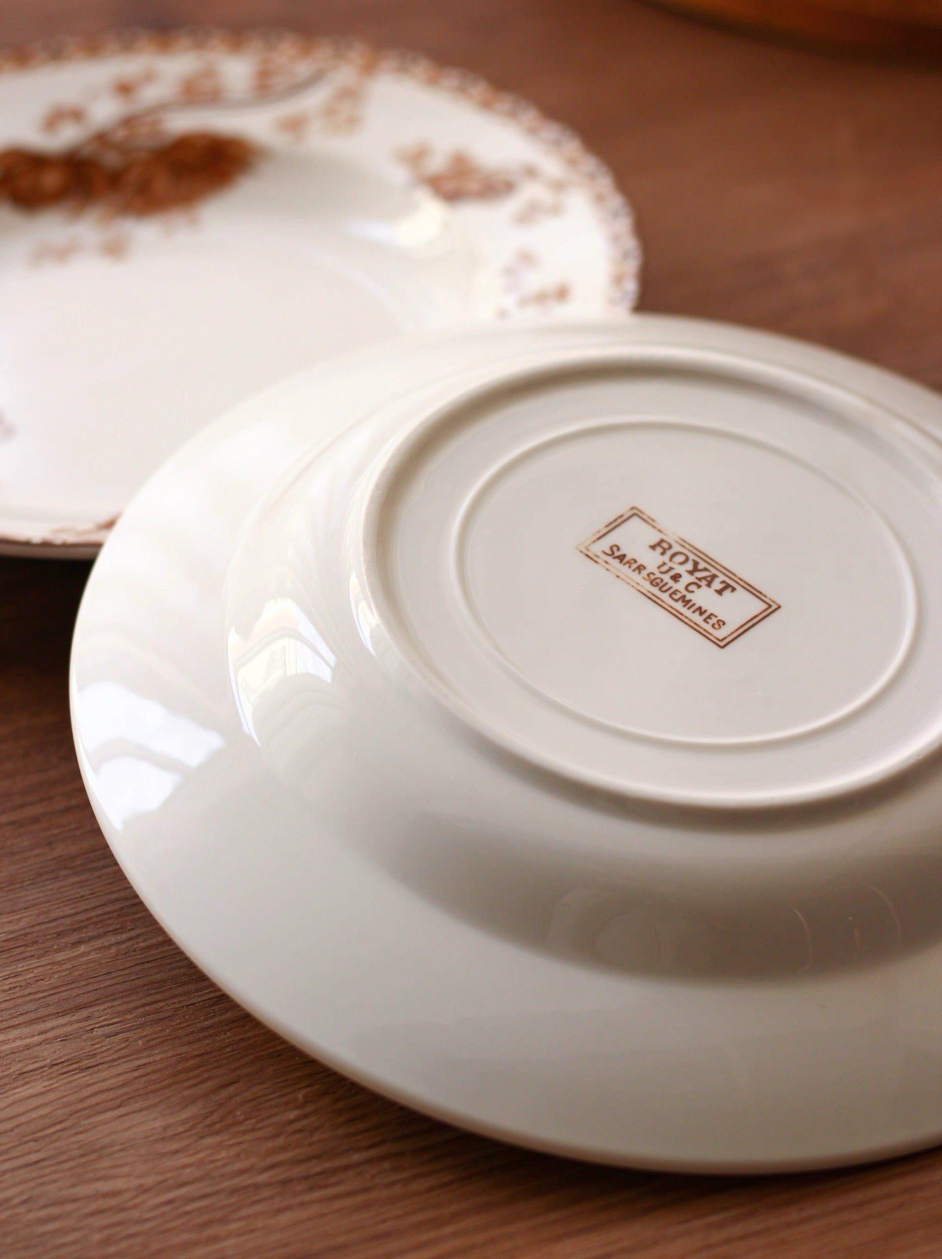White ceramic plate with a brand logo on a wooden surface