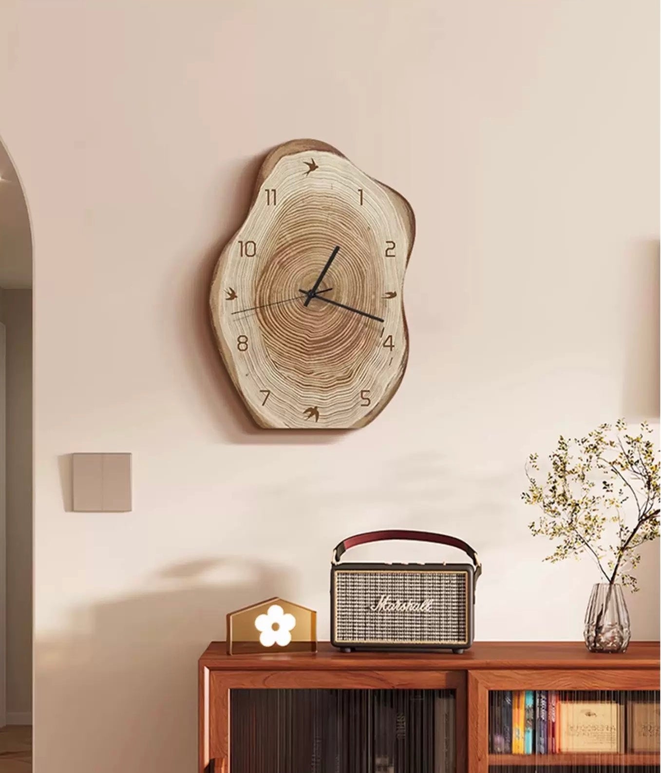 Wooden wall clock on a wall above a wooden console table with a radio and decorative items.