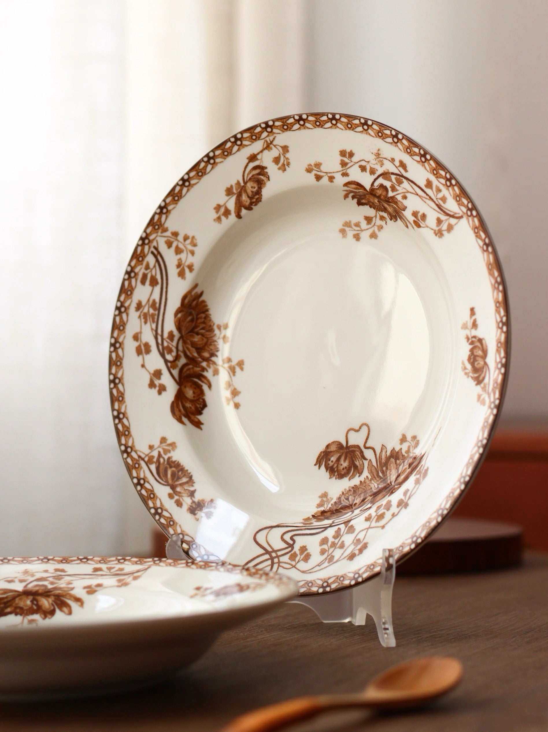 White plate with brown floral patterns on a stand