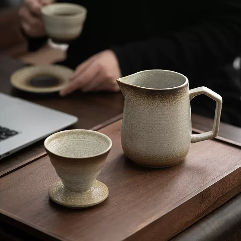 Ceramic pitcher and cup on a wooden surface with blurred background