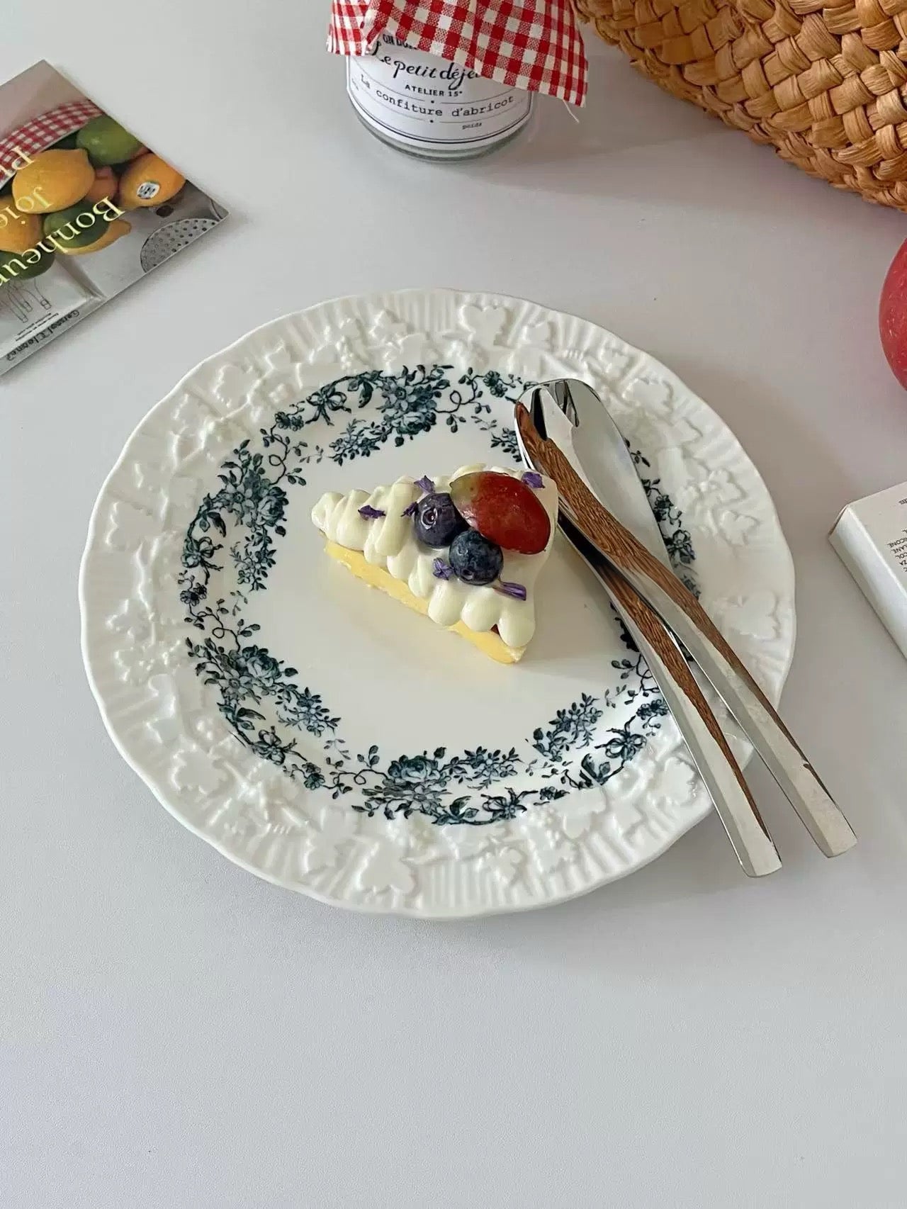 Small dessert with berries on a decorative plate with cutlery, on a light surface.