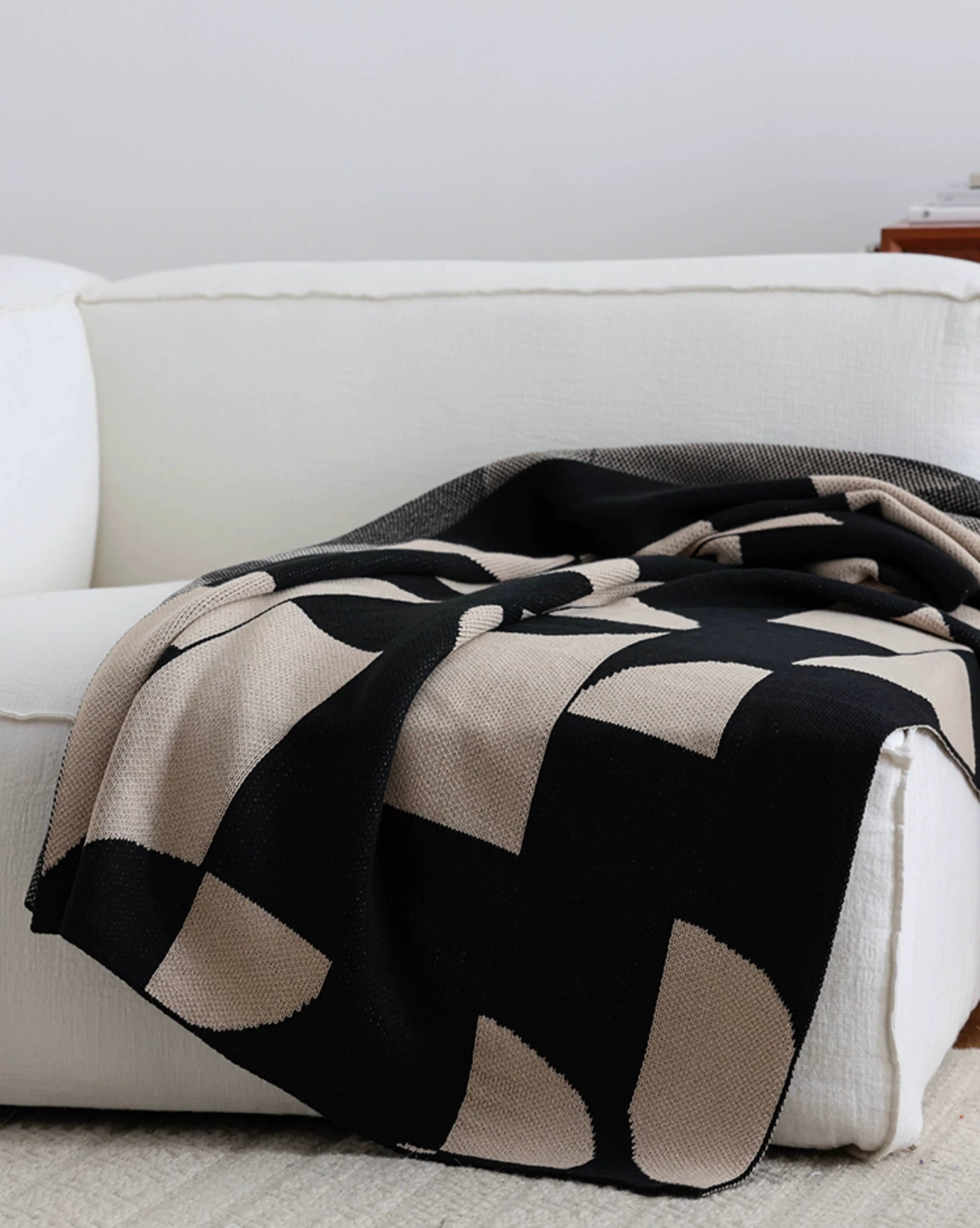 Black and beige patterned blanket draped over a white sofa.